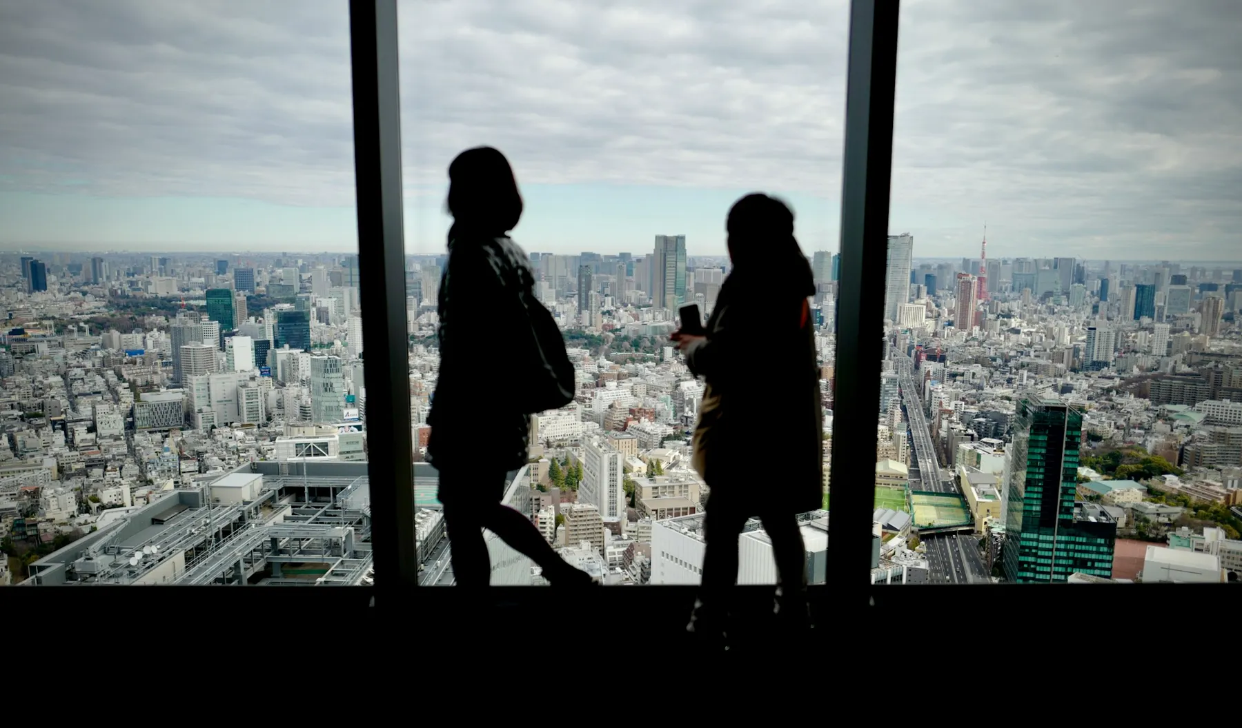 高層ビルの窓から東京の街を眺める2人